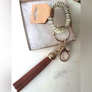 Flexible bracelet and keychain, gold tone with a hanging tassel